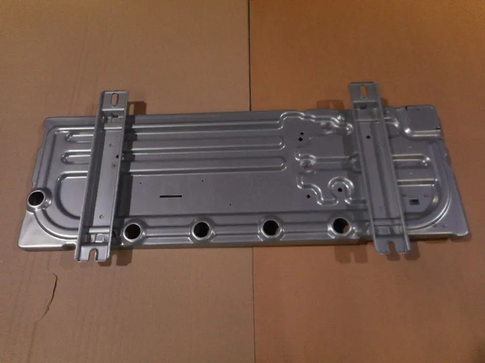 Sockel von Remeha, flaches, metallisches Bauteil mit mehreren Öffnungen und Montagehaltern, auf einem Karton nachgebildet.